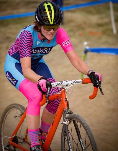 Woman riding a red-orange Zinn cyclocross bicycle on a track